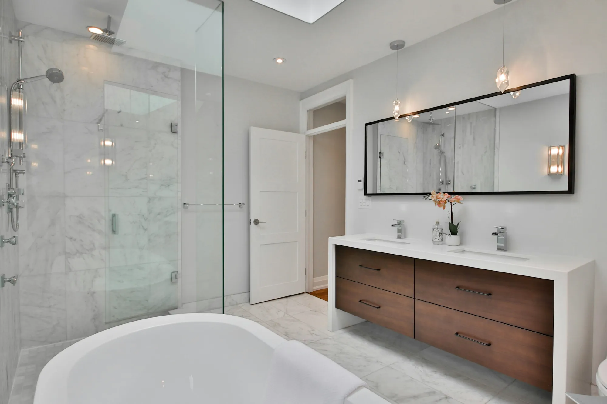Bright bathroom with a marble walk-in glass shower and a floating double vanity