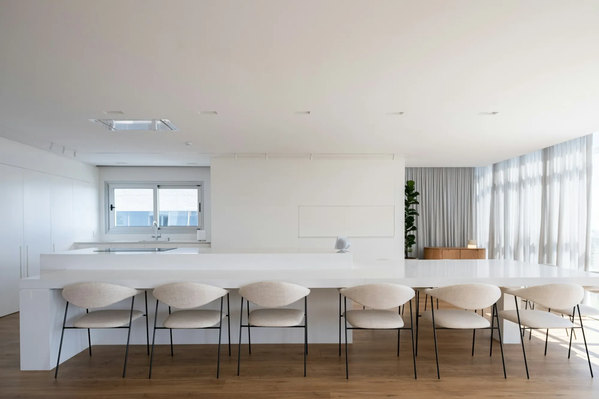 All-white kitchen with a long island and upholstered counter seating