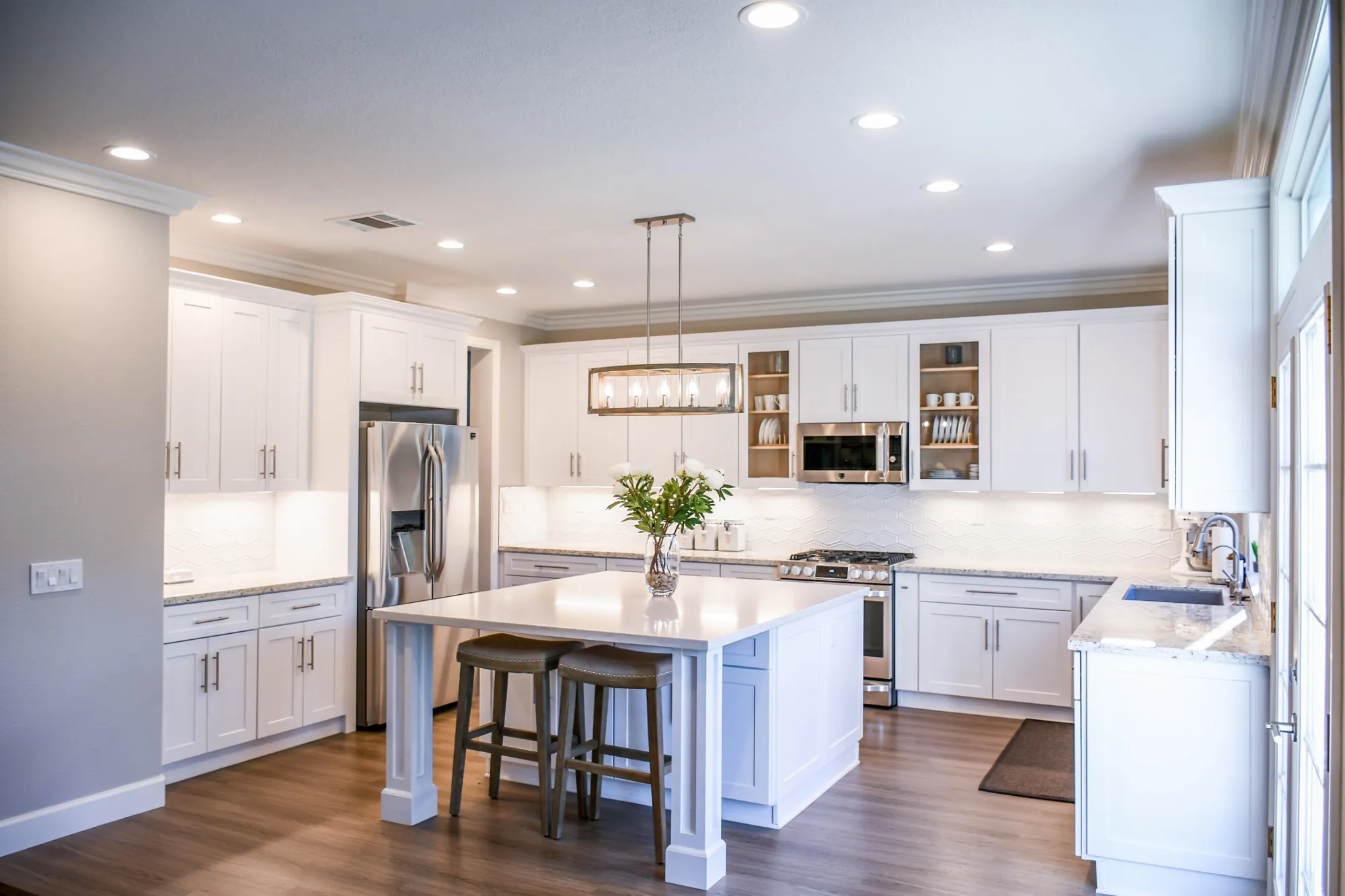 White kitchen with shaker cabinets, island seating and pendant lighting