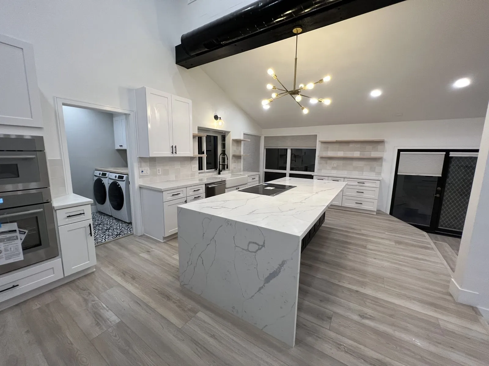 Kitchen remodel with a waterfall quartz island and white shaker cabinets
