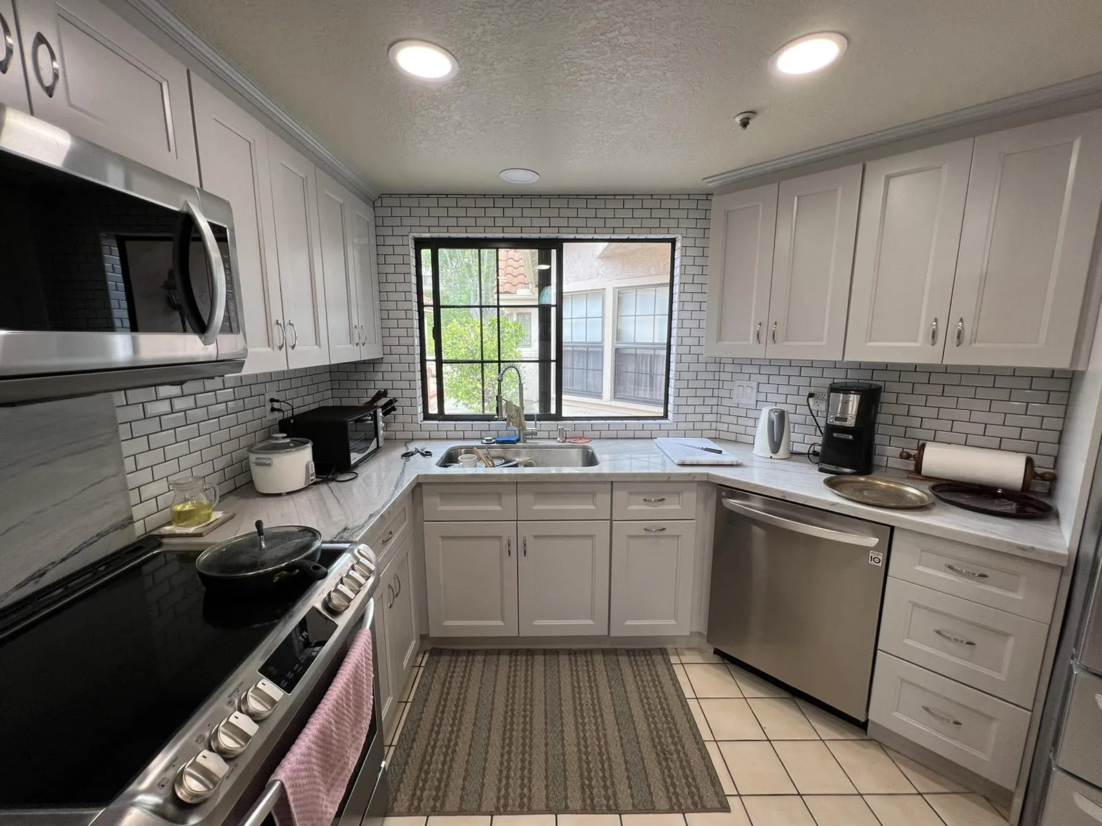 U-shaped kitchen with white shaker cabinets and subway tile backsplash